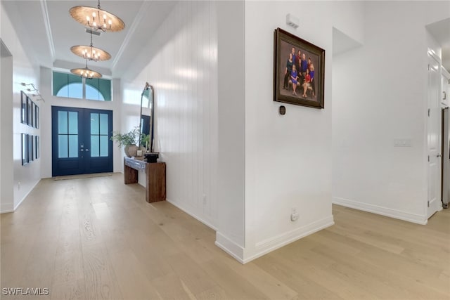 entryway with a tray ceiling, french doors, a chandelier, and light hardwood / wood-style flooring