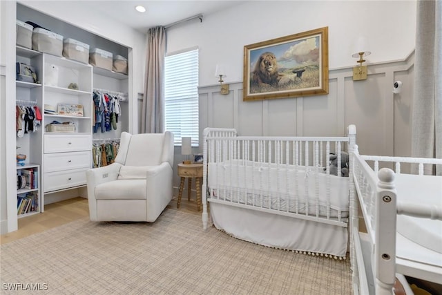 bedroom with a crib, light hardwood / wood-style floors, and a closet