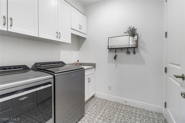 laundry area featuring cabinets, light tile patterned floors, and washing machine and clothes dryer