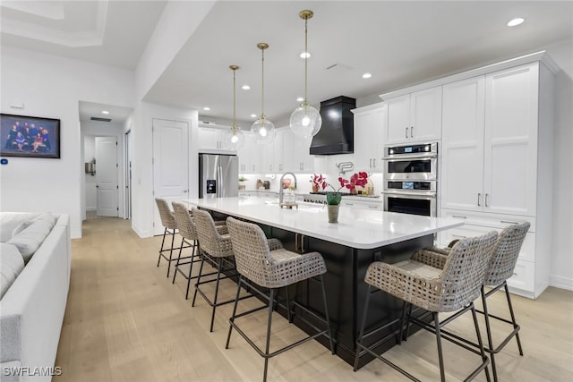 kitchen featuring a large island, a breakfast bar, stainless steel appliances, and decorative light fixtures