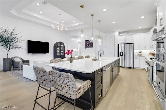 kitchen featuring white cabinets, stainless steel fridge, sink, and a kitchen island with sink