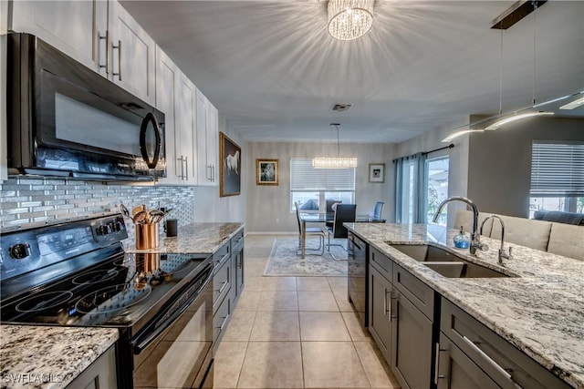 kitchen with sink, black appliances, an inviting chandelier, hanging light fixtures, and light tile patterned flooring