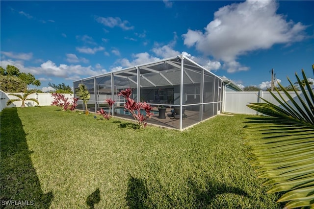 rear view of property with glass enclosure, a patio area, and a lawn