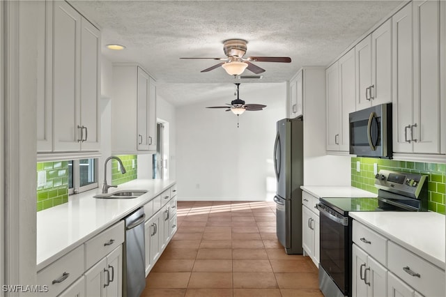 kitchen with sink, light tile patterned floors, ceiling fan, white cabinetry, and stainless steel appliances