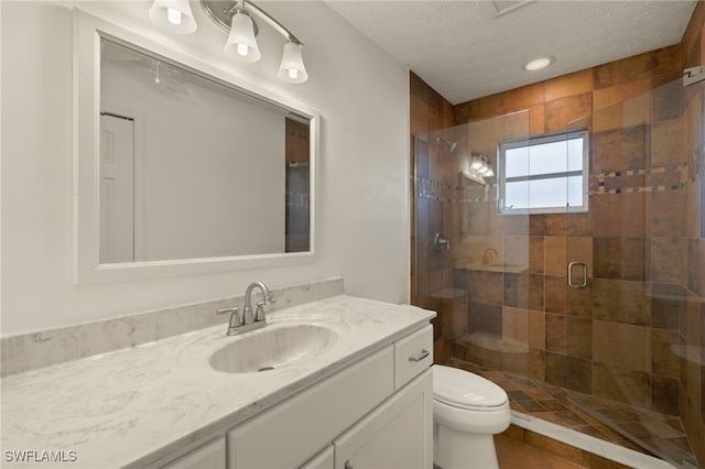 bathroom featuring vanity, a shower with shower door, a textured ceiling, and toilet