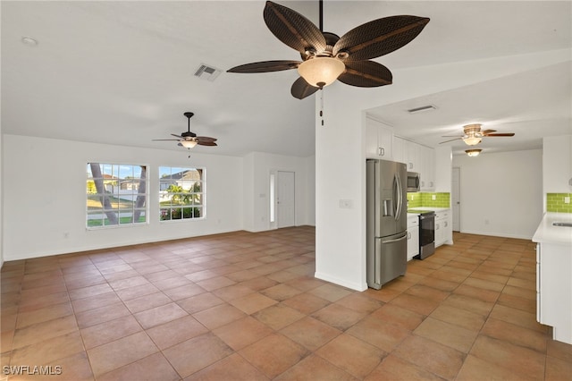 kitchen with stainless steel appliances, light tile patterned floors, decorative backsplash, and white cabinets