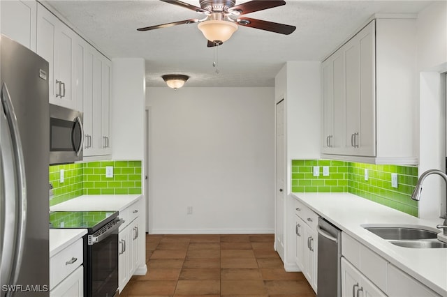 kitchen featuring sink, appliances with stainless steel finishes, tasteful backsplash, white cabinets, and dark tile patterned flooring