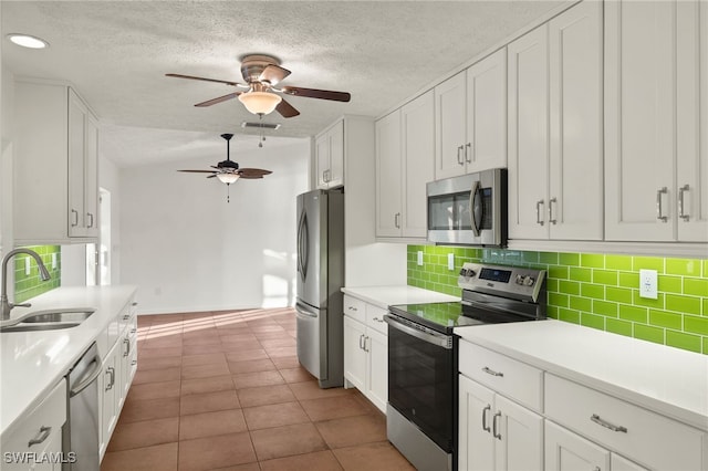 kitchen with sink, white cabinetry, appliances with stainless steel finishes, tile patterned flooring, and backsplash