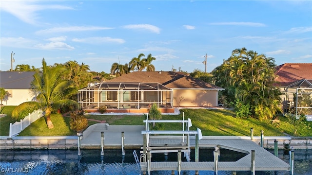 rear view of property with a water view, glass enclosure, and a lawn