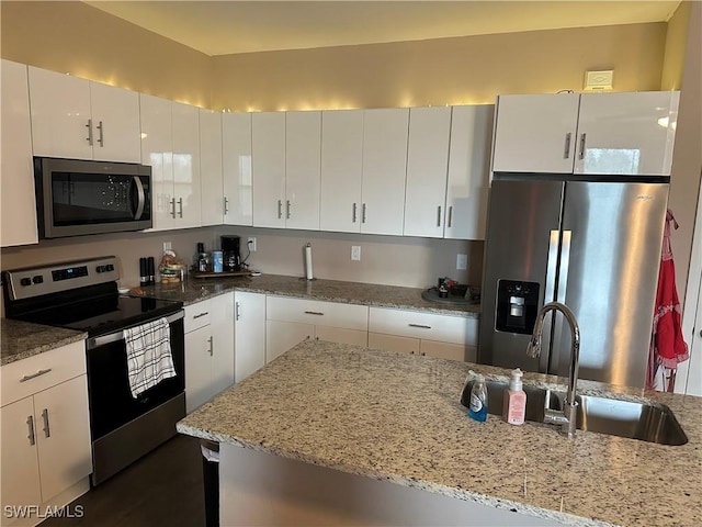 kitchen featuring light stone countertops, sink, white cabinetry, and stainless steel appliances