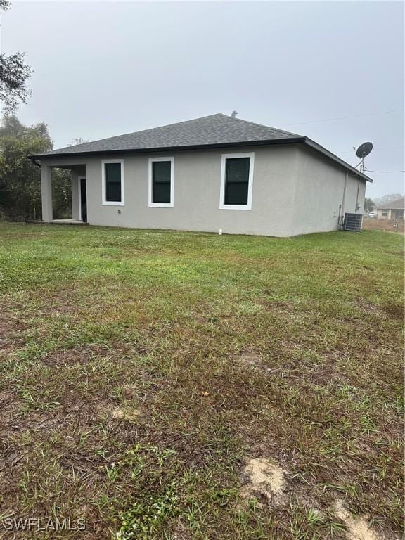 view of side of property featuring a yard and central AC