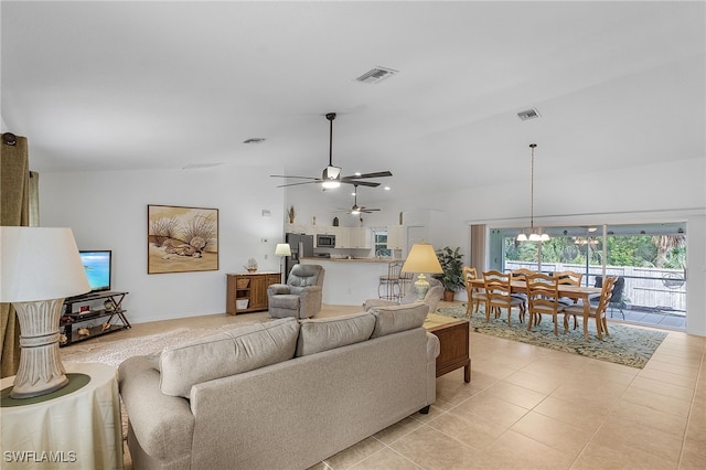 living room with ceiling fan with notable chandelier, light tile patterned floors, and lofted ceiling