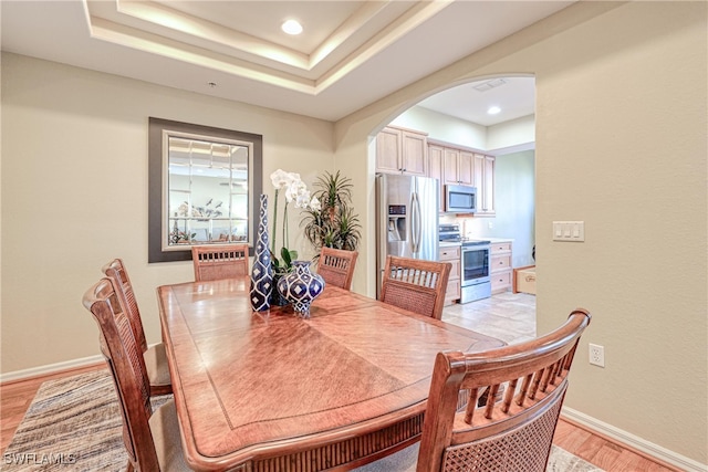 dining area with a tray ceiling and light hardwood / wood-style floors