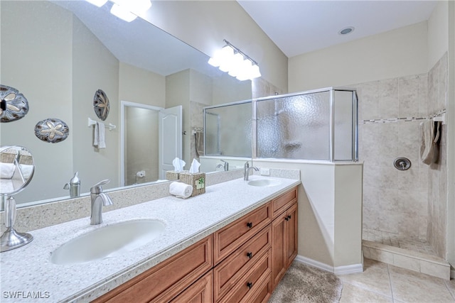 bathroom with tile patterned flooring, a tile shower, and vanity