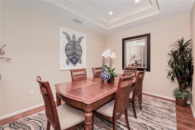 dining space with a tray ceiling and hardwood / wood-style flooring