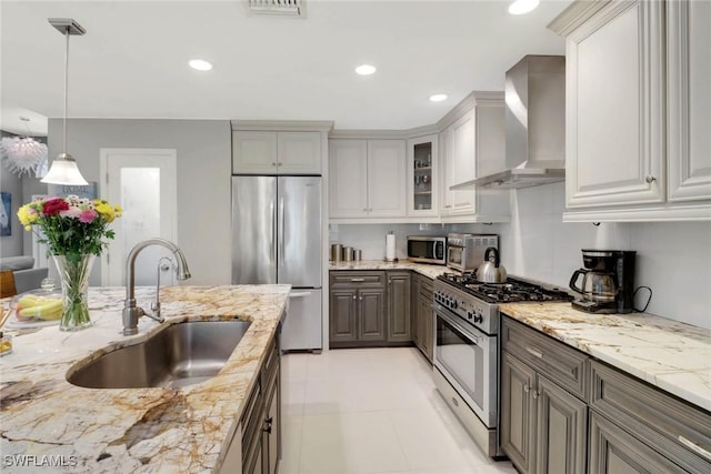 kitchen with gray cabinets, sink, hanging light fixtures, stainless steel appliances, and wall chimney exhaust hood