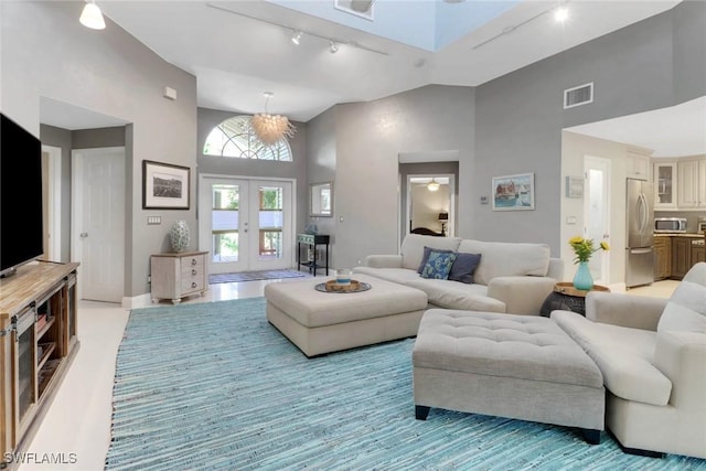 living room with track lighting, high vaulted ceiling, and french doors