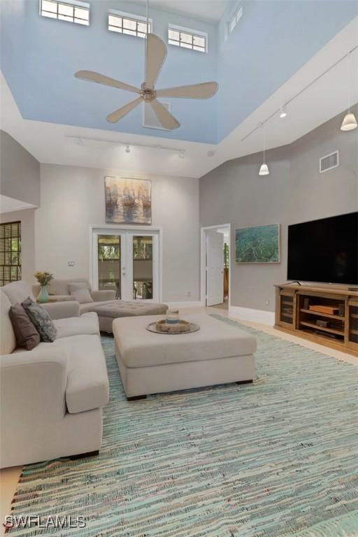 living room featuring a high ceiling, ceiling fan, and french doors