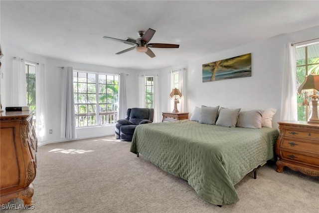 bedroom featuring multiple windows, light carpet, and ceiling fan