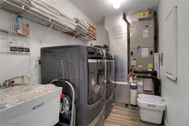 laundry room featuring wood-type flooring, sink, and washing machine and dryer