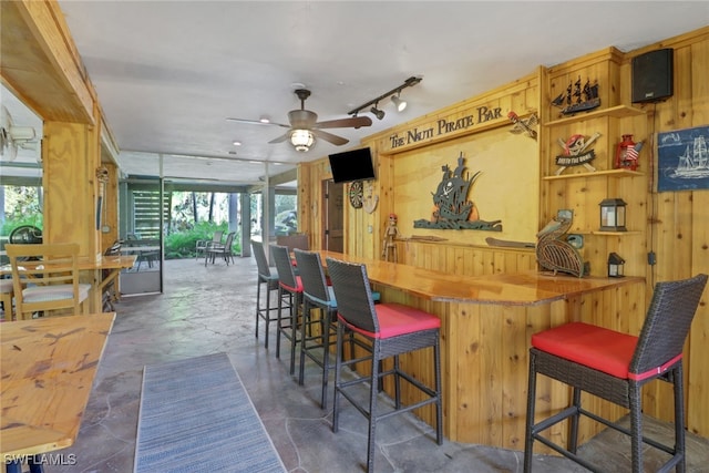 interior space featuring wooden walls, a kitchen breakfast bar, kitchen peninsula, and butcher block counters