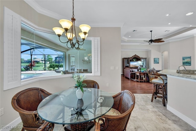 dining room featuring a raised ceiling, crown molding, and ceiling fan with notable chandelier