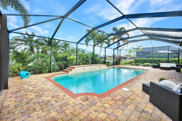 view of pool featuring glass enclosure, an outdoor hangout area, and a patio