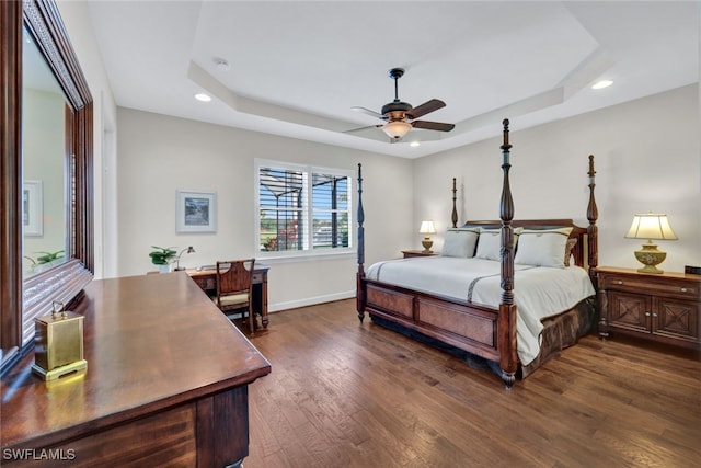 bedroom with dark hardwood / wood-style flooring, a raised ceiling, and ceiling fan