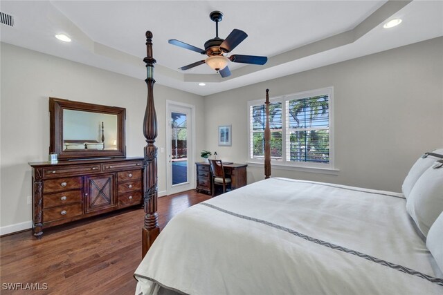 bedroom featuring a tray ceiling, ceiling fan, dark hardwood / wood-style flooring, and access to outside