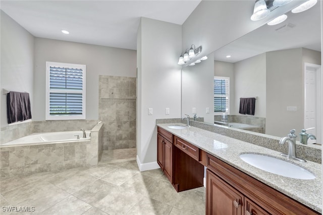 bathroom with tile patterned flooring, vanity, and tiled bath