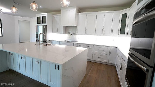 kitchen featuring pendant lighting, a center island with sink, sink, stainless steel fridge with ice dispenser, and white cabinetry