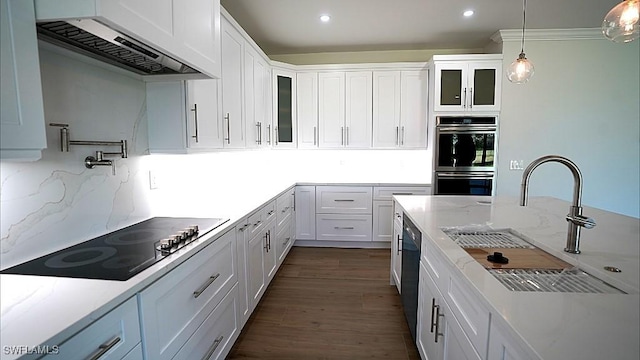 kitchen with custom exhaust hood, stainless steel double oven, sink, stovetop, and white cabinets