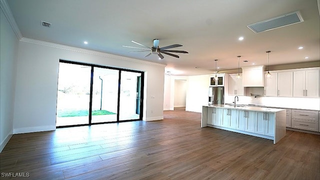 kitchen with stainless steel fridge, a kitchen island with sink, ceiling fan, white cabinetry, and hanging light fixtures