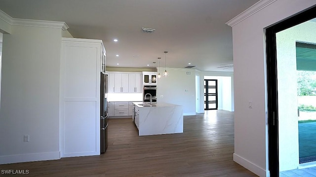 kitchen with white cabinetry, a center island with sink, decorative light fixtures, and sink