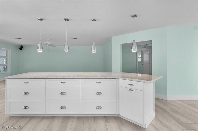 kitchen featuring light stone counters, decorative light fixtures, light wood-style flooring, and white cabinetry