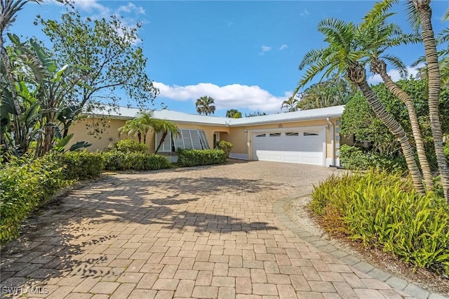 ranch-style home with an attached garage, decorative driveway, and stucco siding