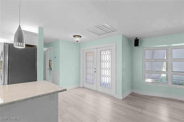 foyer featuring light wood-type flooring, baseboards, and french doors