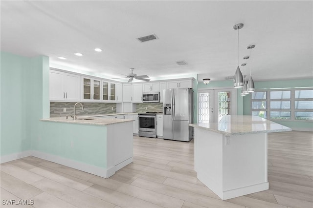 kitchen with appliances with stainless steel finishes, a sink, glass insert cabinets, and decorative backsplash