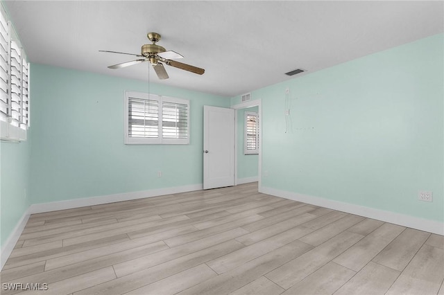 unfurnished room featuring baseboards, visible vents, ceiling fan, and wood finished floors