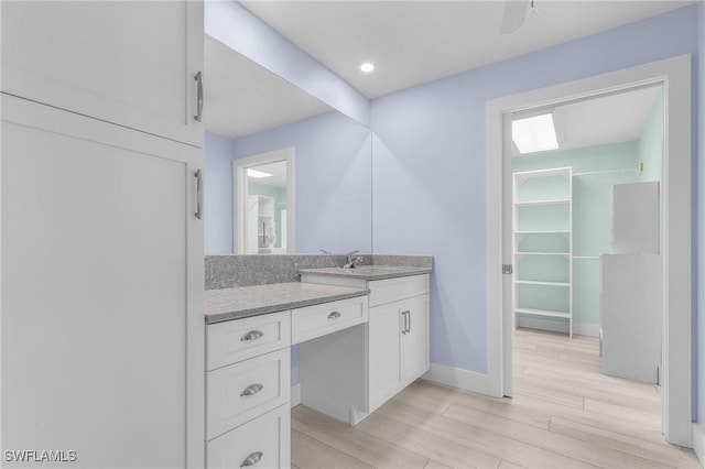 bathroom featuring wood finished floors, vanity, and baseboards