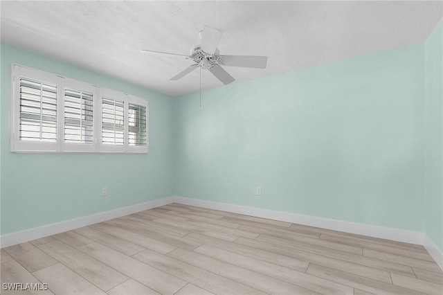 spare room with ceiling fan, light wood finished floors, and baseboards