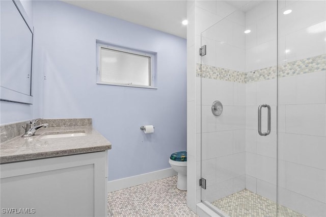 bathroom featuring toilet, a stall shower, vanity, tile patterned flooring, and baseboards