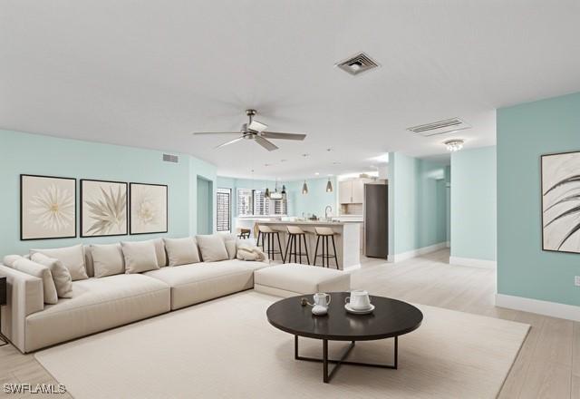 living area featuring ceiling fan, baseboards, visible vents, and light wood-style floors