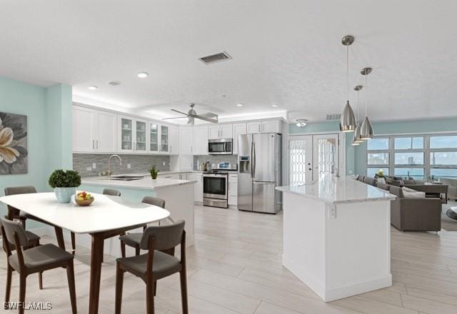 kitchen featuring tasteful backsplash, glass insert cabinets, stainless steel appliances, light countertops, and white cabinetry