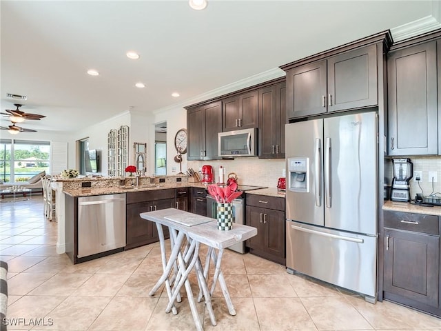 kitchen with dark brown cabinets, backsplash, and appliances with stainless steel finishes