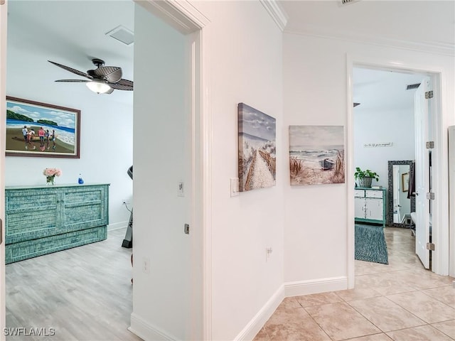 corridor featuring light tile patterned floors and crown molding