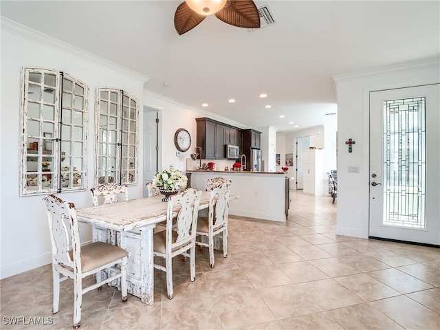 tiled dining room with crown molding, sink, and ceiling fan