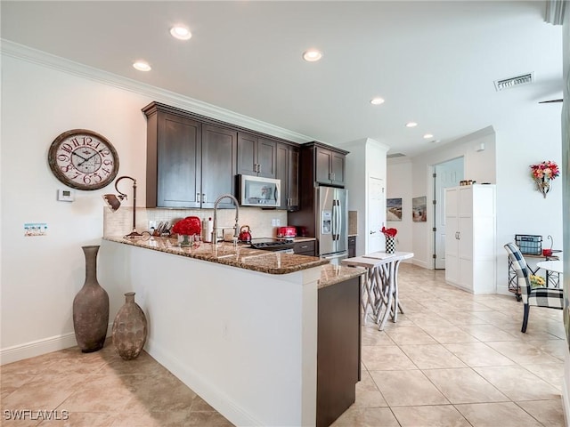 kitchen with crown molding, decorative backsplash, dark stone countertops, appliances with stainless steel finishes, and kitchen peninsula