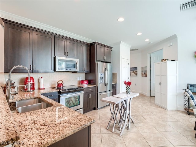 kitchen with dark brown cabinetry, sink, stainless steel appliances, tasteful backsplash, and light stone counters