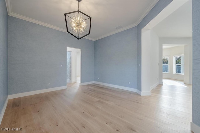 spare room with a chandelier, light wood-type flooring, and ornamental molding